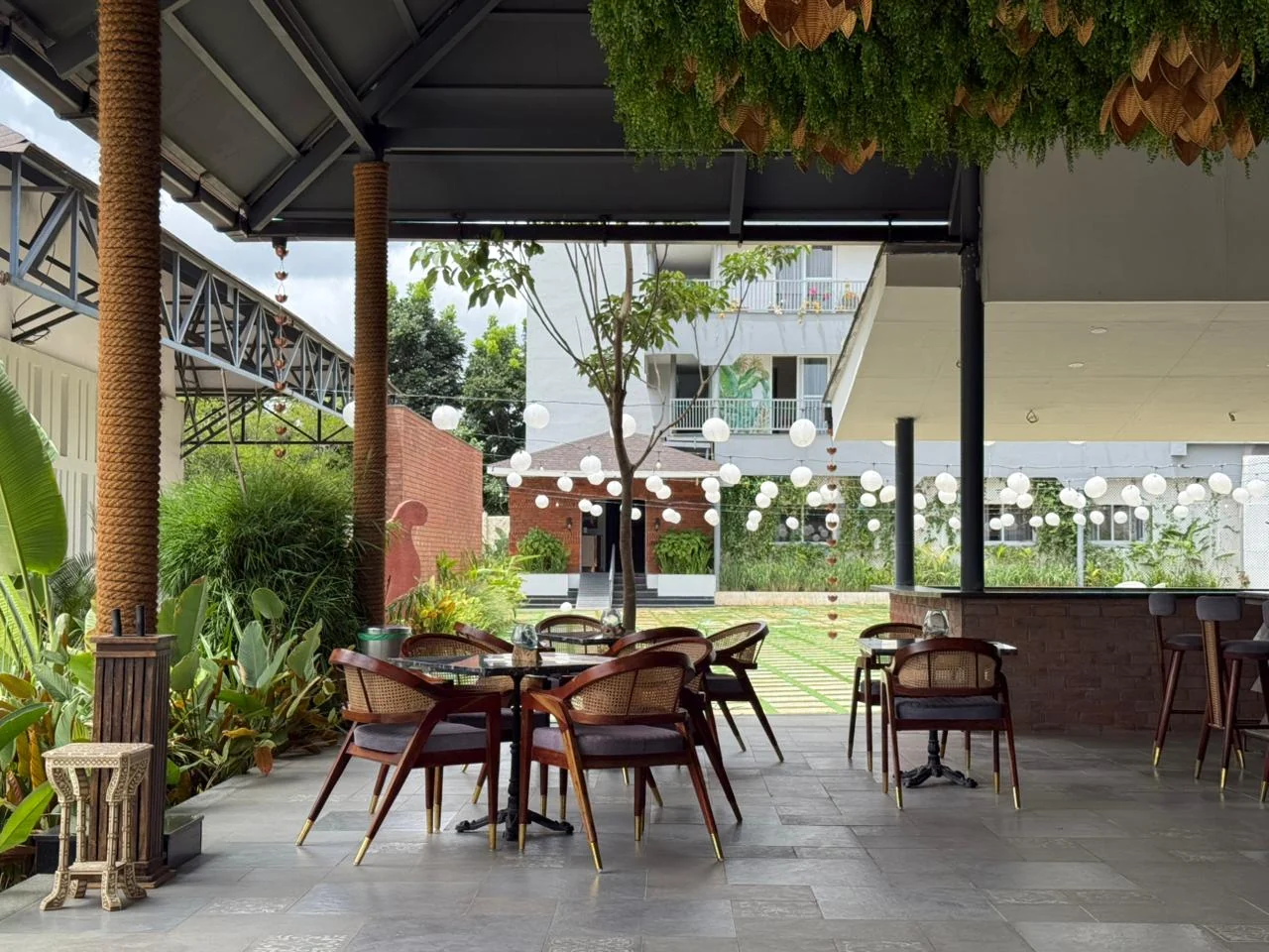 Restaurant tables beneath a botanical canopy overlooking the courtyard