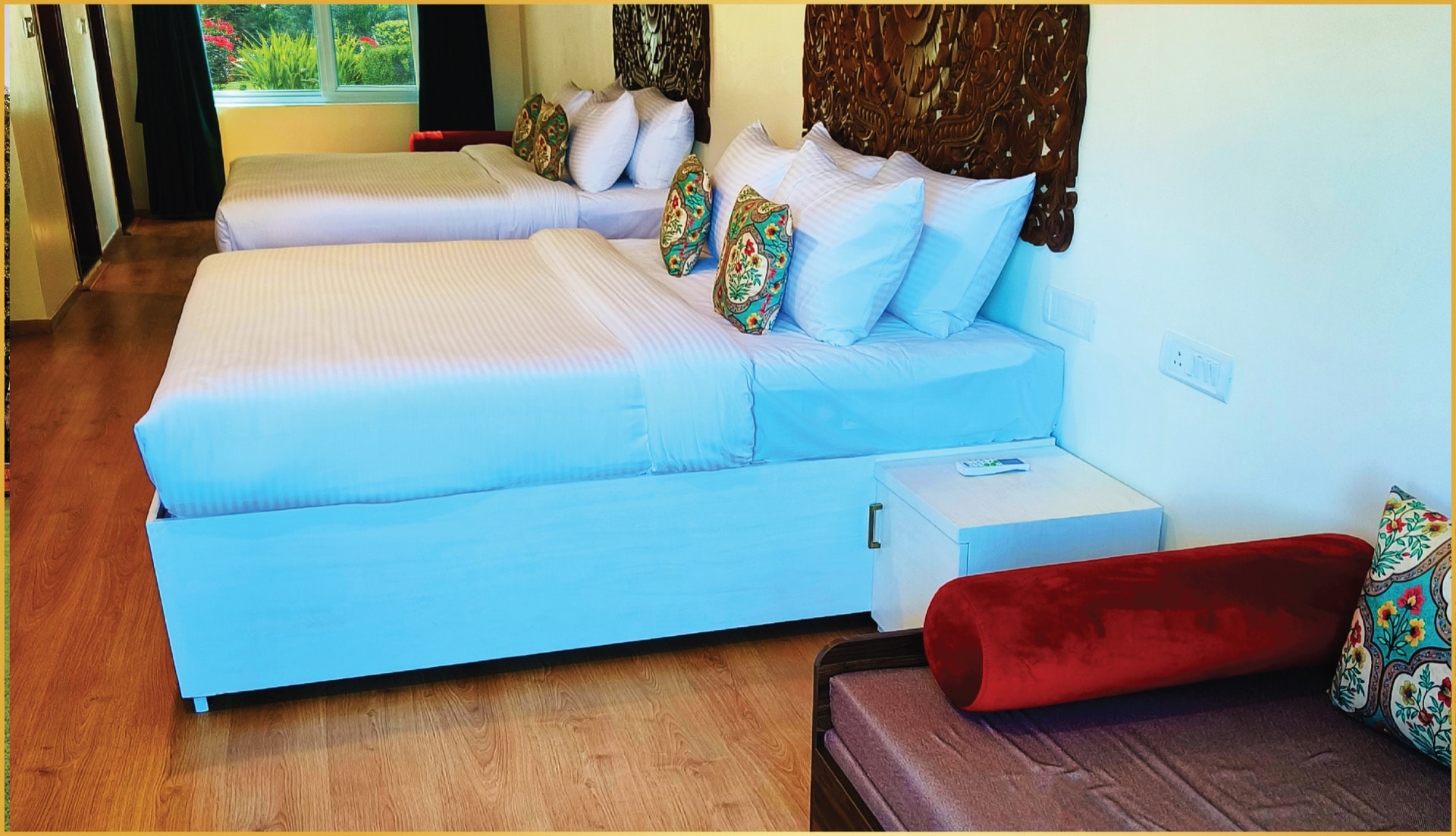 Twin room with Balinese carved headboard, floral cushions, and wooden flooring